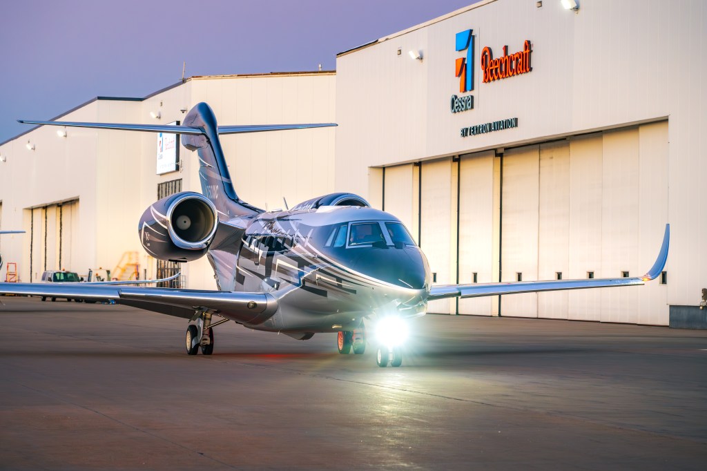 A private jet parked in front of a hangar.